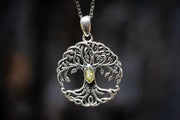 Silver tree of life  pendant with a green gemstone and cremation ash on a dark background